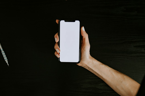 Hand holding a smartphone with a blank screen against a dark background